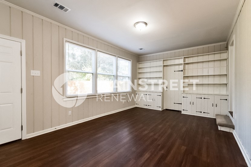 an empty living room with wood floors and a large window