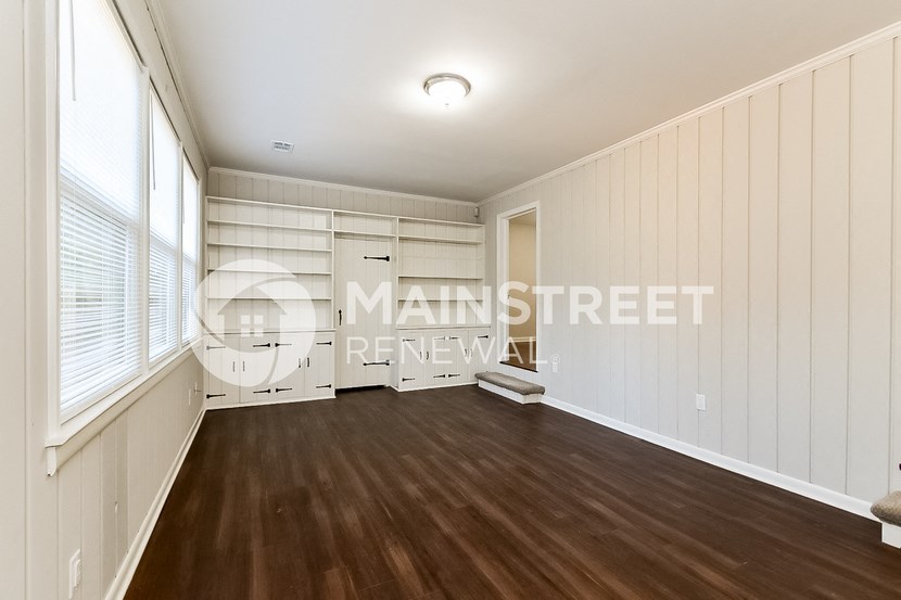 a living room with wood floors and white walls and a window