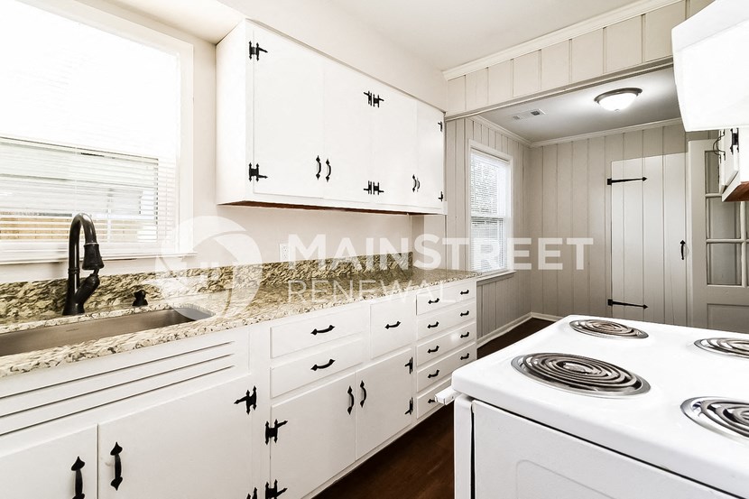 a white kitchen with white cabinets and granite counter tops