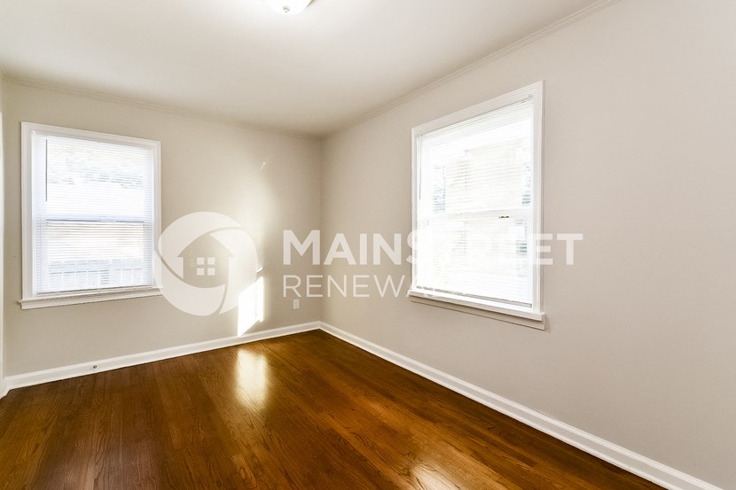 white bedroom with two windows and a wood floor