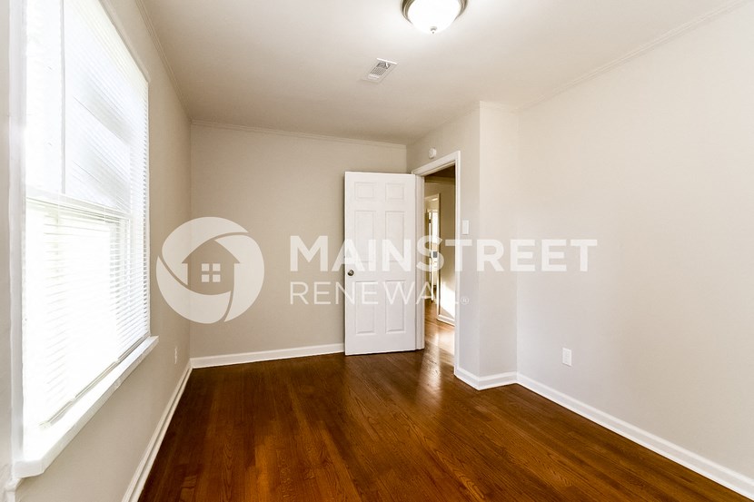 a bedroom with hardwood flooring and a door to a closet