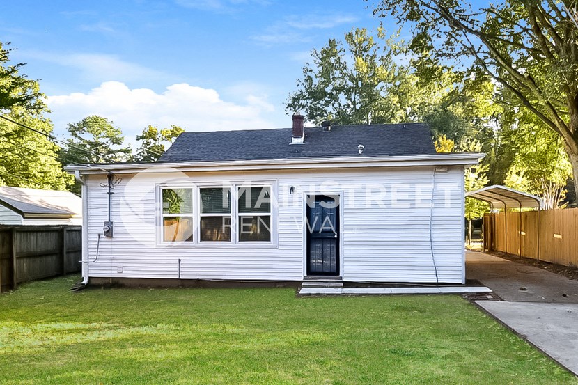 a small white house with a black door and a yard