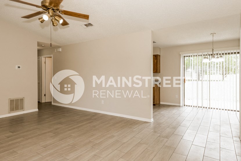 a large living room with a large window and a ceiling fan