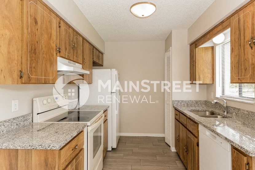 a kitchen with wood cabinets and white appliances and granite counter tops