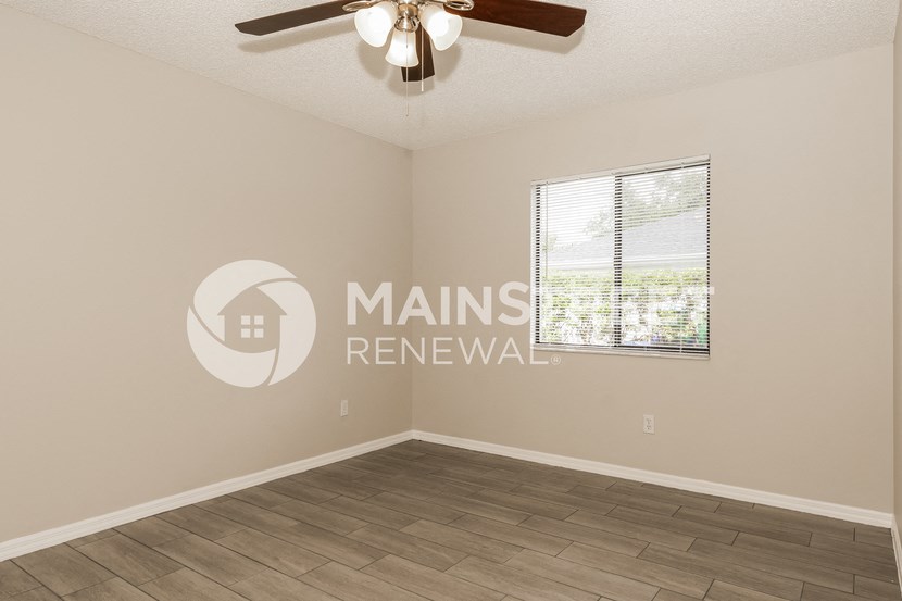 an empty living room with a ceiling fan and a window