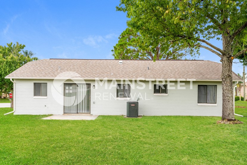 a small white house with a yard and a tree