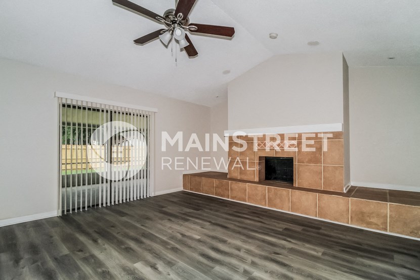 a living room with a fireplace and a ceiling fan
