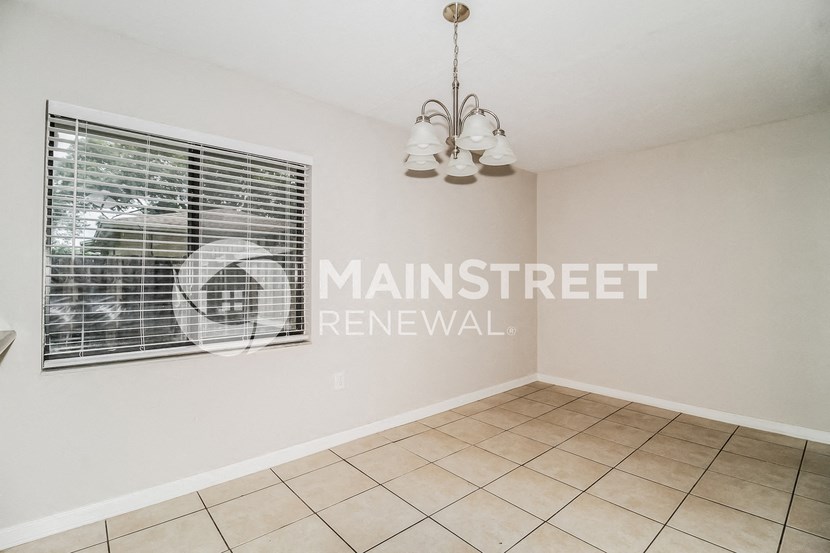 a renovated living room with a large window and a tiled floor