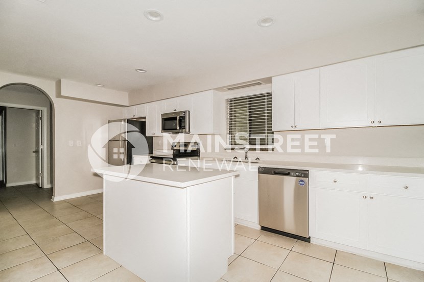 a renovated kitchen with white cabinets and stainless steel appliances