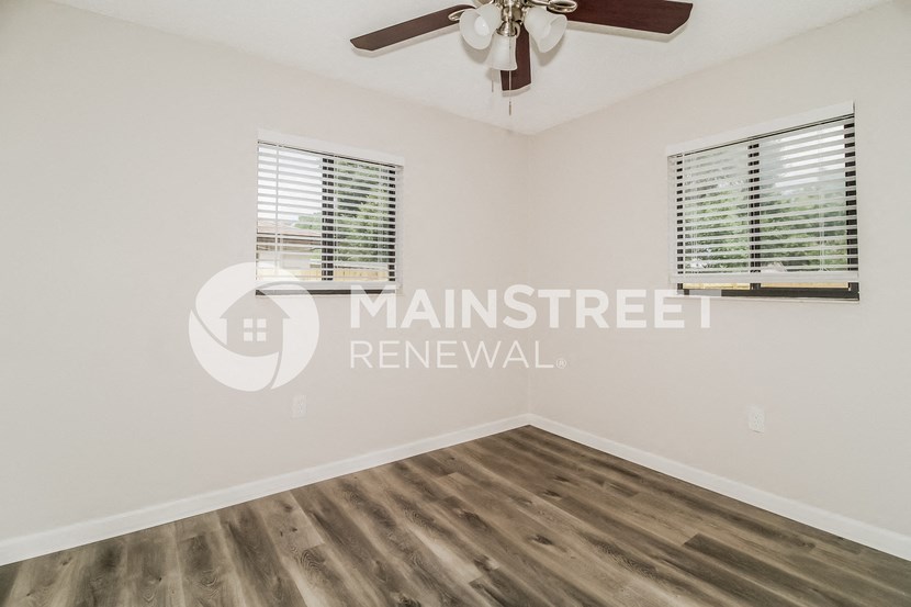 a bedroom with a ceiling fan and two windows