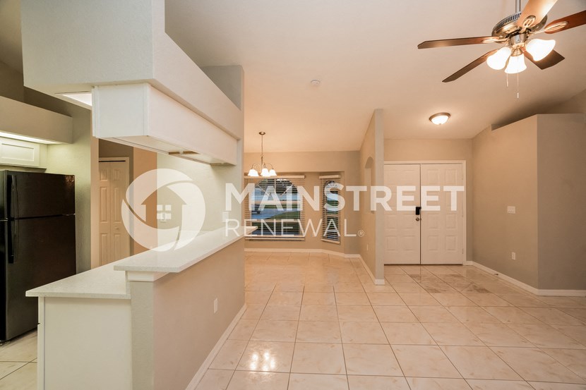 a large living room with a kitchen and a ceiling fan
