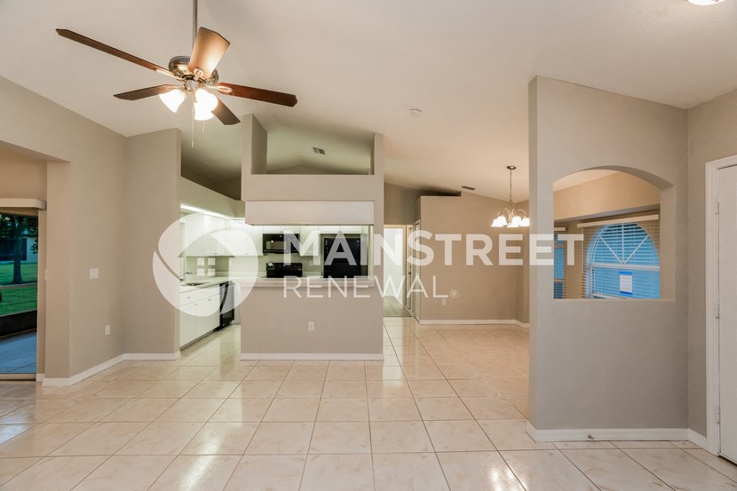 a renovated living room with a large tile floor and a ceiling fan