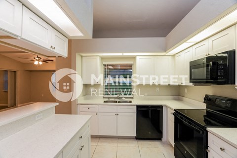 a renovated kitchen with white cabinets and black appliances