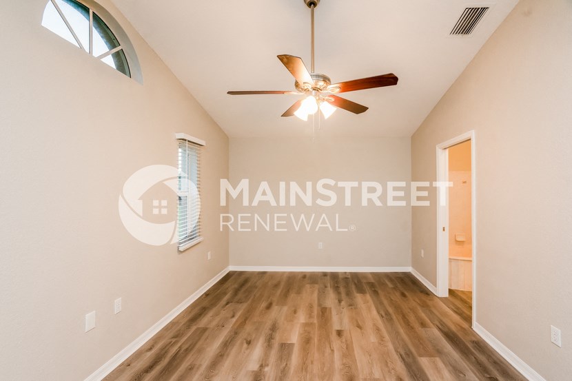 a living room with a ceiling fan and a door to a closet