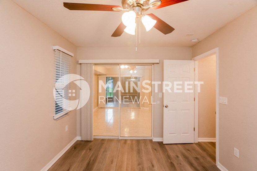 a bedroom with a ceiling fan and a door to a closet