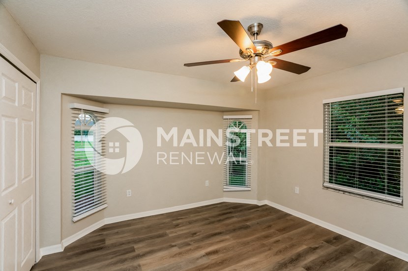 an empty living room with a ceiling fan and a window