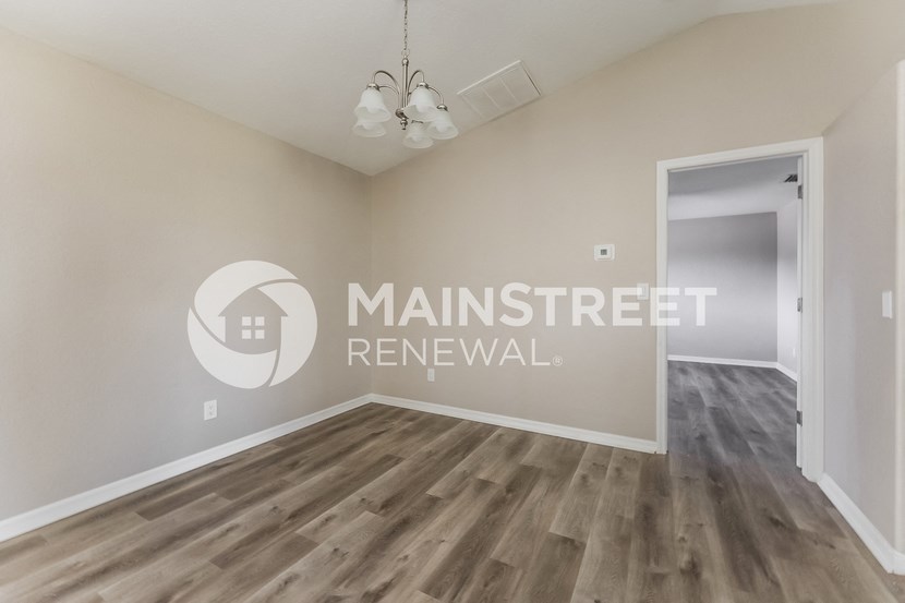 a renovated living room with hardwood floors and a door to a hallway