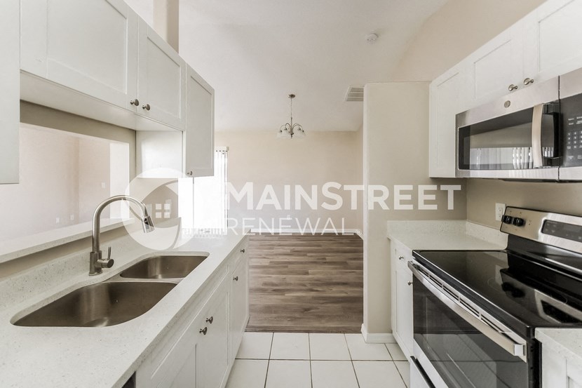 a renovated kitchen with white cabinets and stainless steel appliances