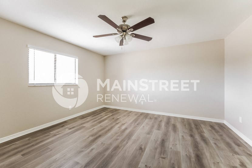 an empty room with a ceiling fan and a window