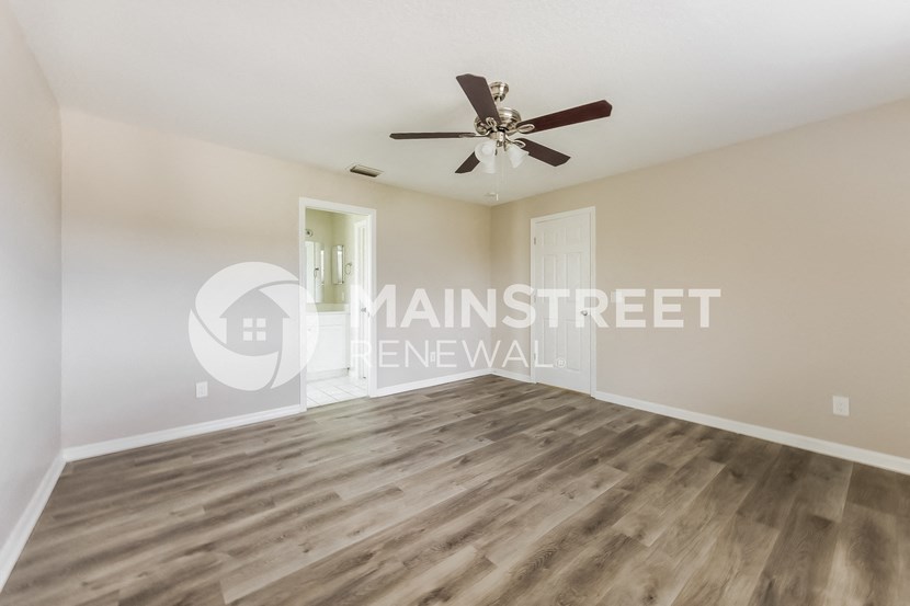a spacious living room with hardwood floors and a ceiling fan