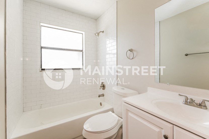 a white bathroom with a tub and a sink and a toilet