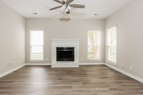 an empty living room with a fireplace and a ceiling fan