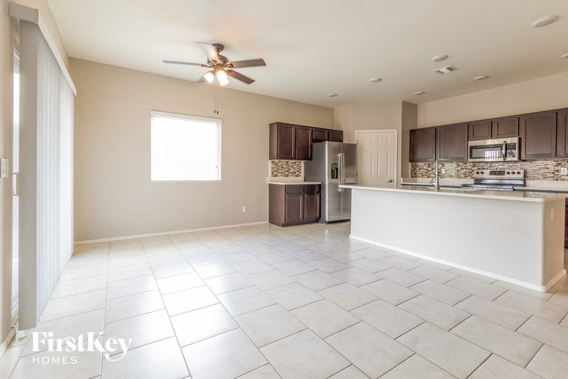 A spacious kitchen and living room with a tile floor and a ceiling fan.