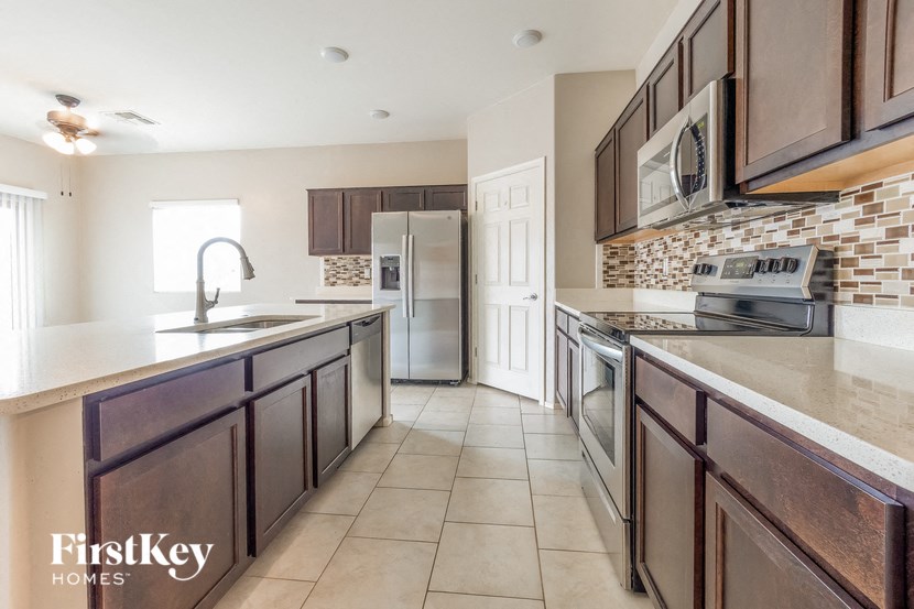 A kitchen with brown cabinets and a tile backsplash.