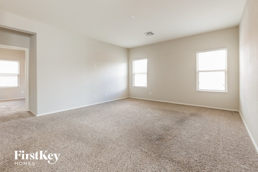 A spacious room with carpeted floor and two windows.