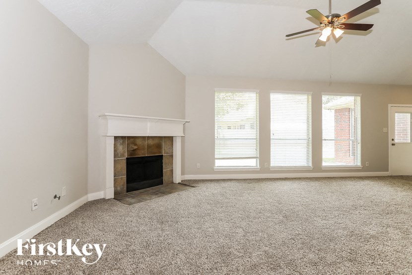 A spacious living room with a fireplace and a ceiling fan.