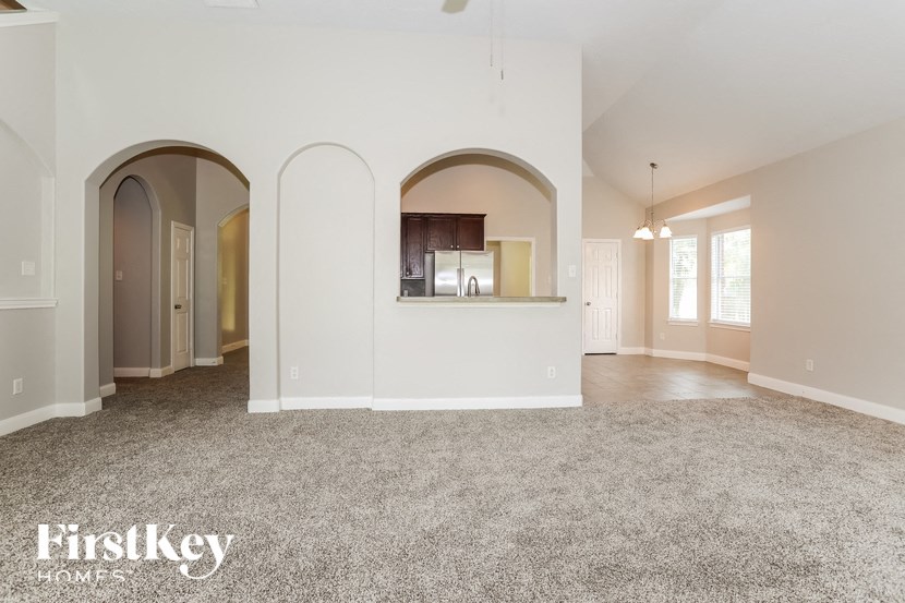 A spacious living room with arched doorways and a carpeted floor.