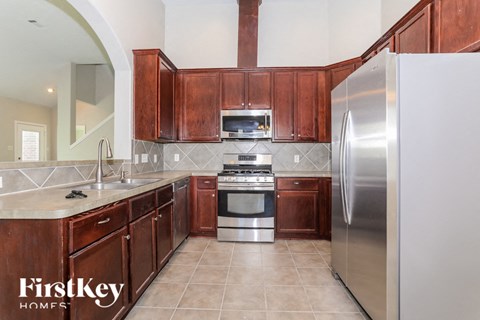 A kitchen with wooden cabinets and a stainless steel refrigerator.