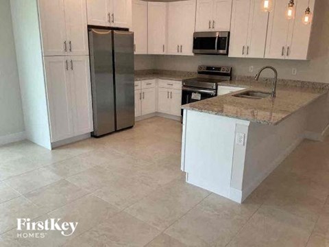 a kitchen with white cabinets and a stainless steel refrigerator