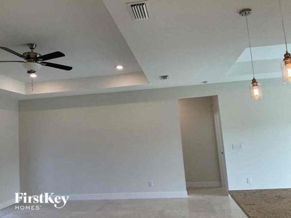 an empty living room with a ceiling fan and lights