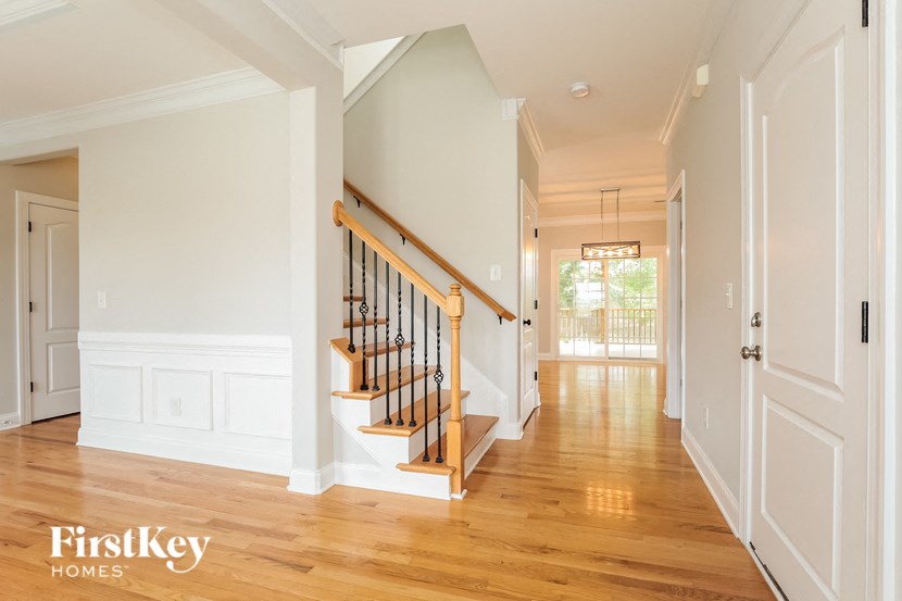 A hallway with a staircase and a door on the right.