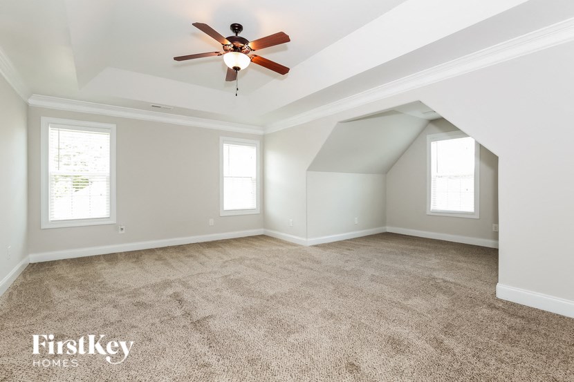 A room with a ceiling fan and two windows.
