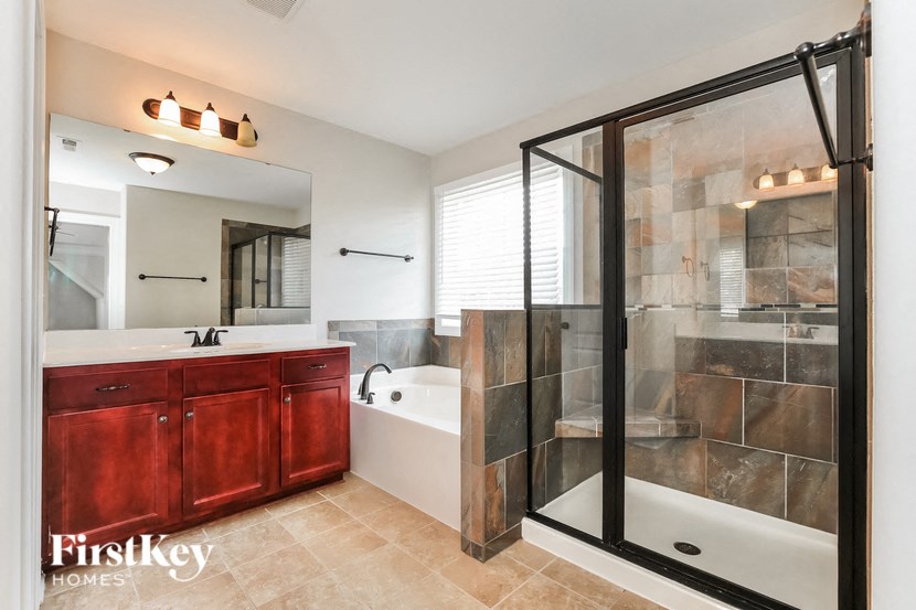 A bathroom with a red cabinet and a glass shower stall.