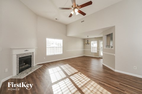 A spacious living room with a fireplace and a ceiling fan.