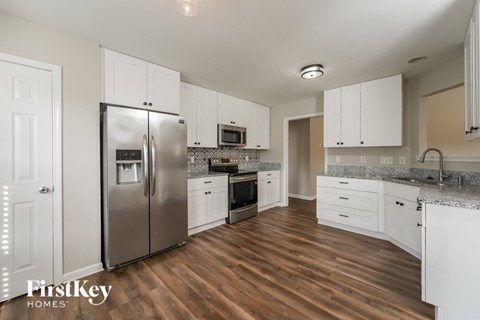 A kitchen with wooden floors and white cabinets.