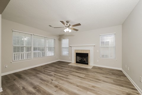an empty living room with a fireplace and a ceiling fan