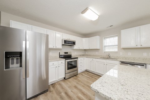a large kitchen with white cabinets and stainless steel appliances