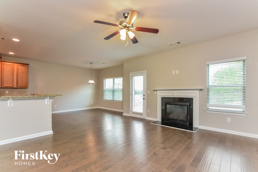 an empty living room with a fireplace and a ceiling fan