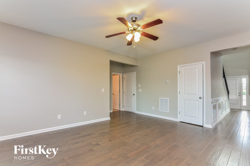 an empty living room with a ceiling fan and wood floors