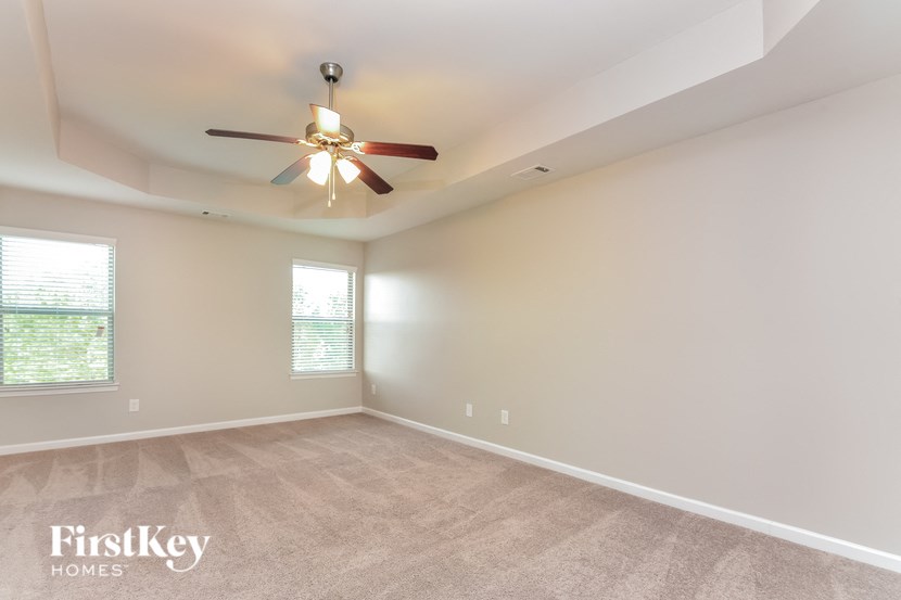 the spacious living room with ceiling fan and carpeting