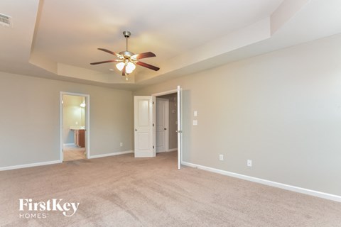 a spacious living room with carpet and a ceiling fan