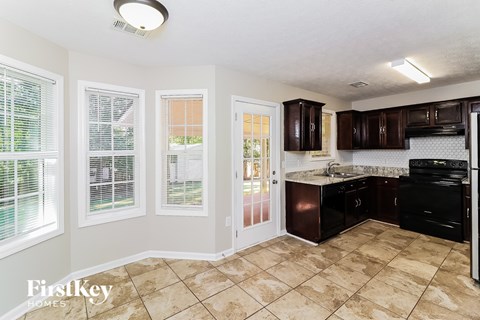 A kitchen with brown cabinets and a tile floor.