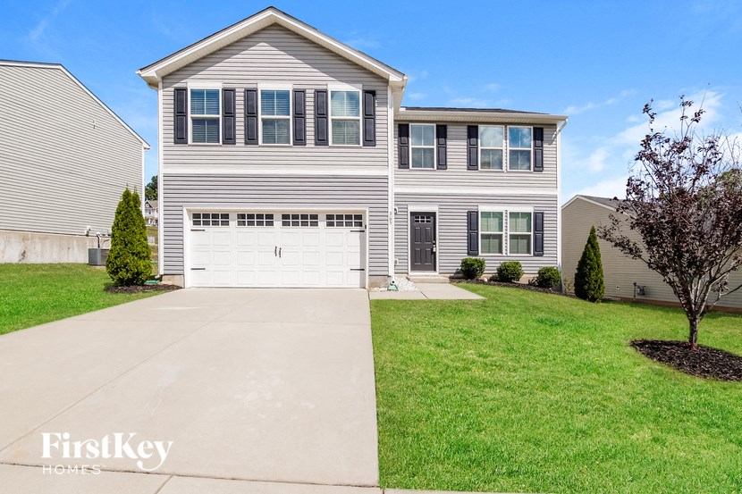 a white house with a white garage door in front of a lawn