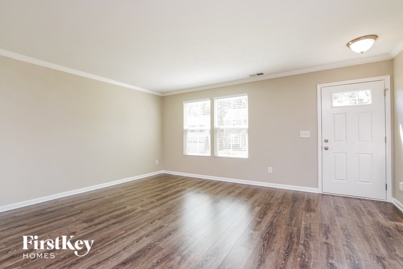 the spacious living room with hardwood flooring and a white door