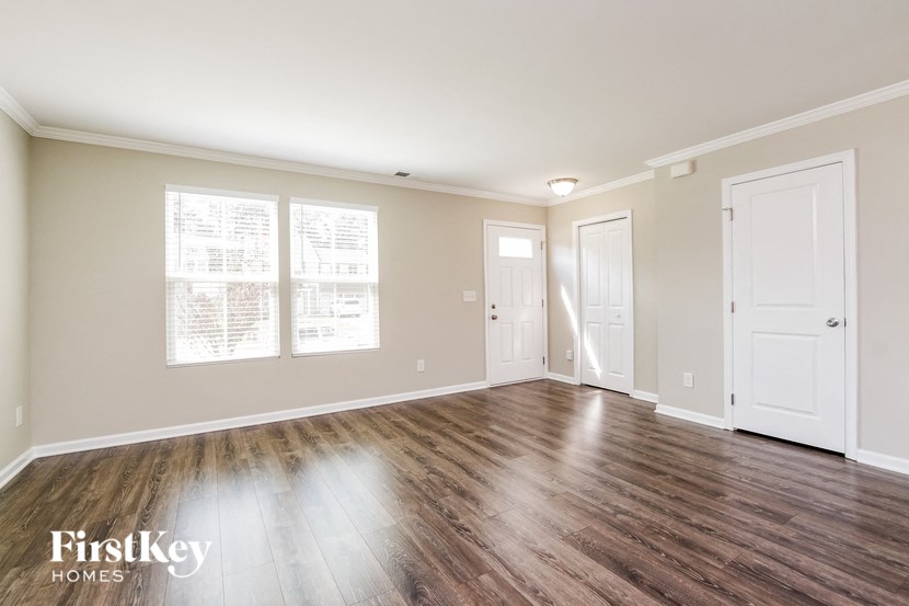 the living room of an empty house with wood floors and white doors