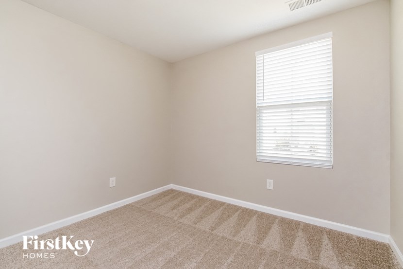 a bedroom with a window and a carpeted floor